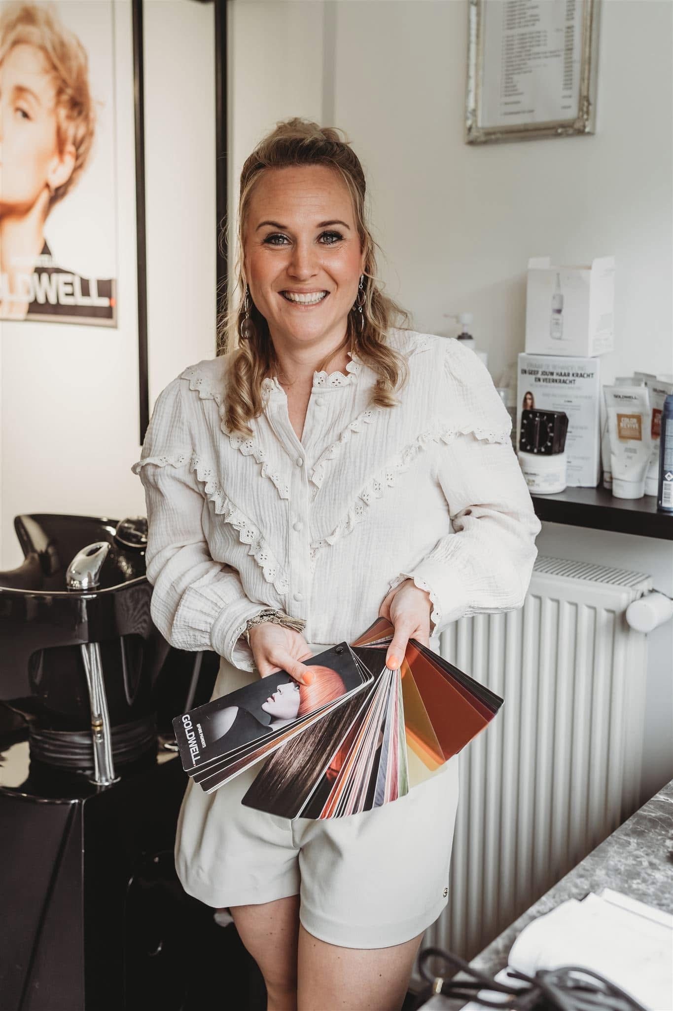 Een salonprofessional met een kleurenwaaier in haar salon